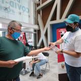 Un hombre recibe ayuda de un voluntario de vacunacion