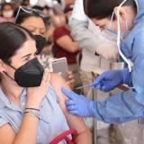 Una enfermera aplica una dosis de la vacuna a una mujer joven
