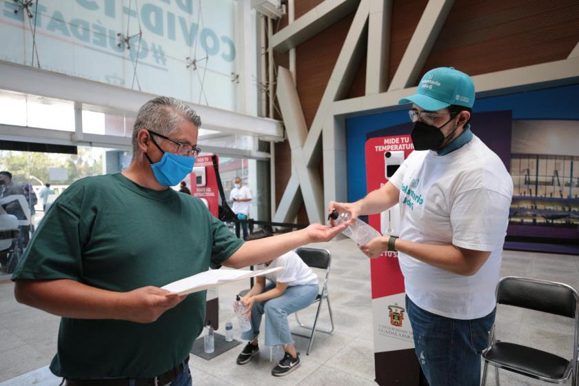 Un hombre recibe ayuda de un voluntario de vacunacion